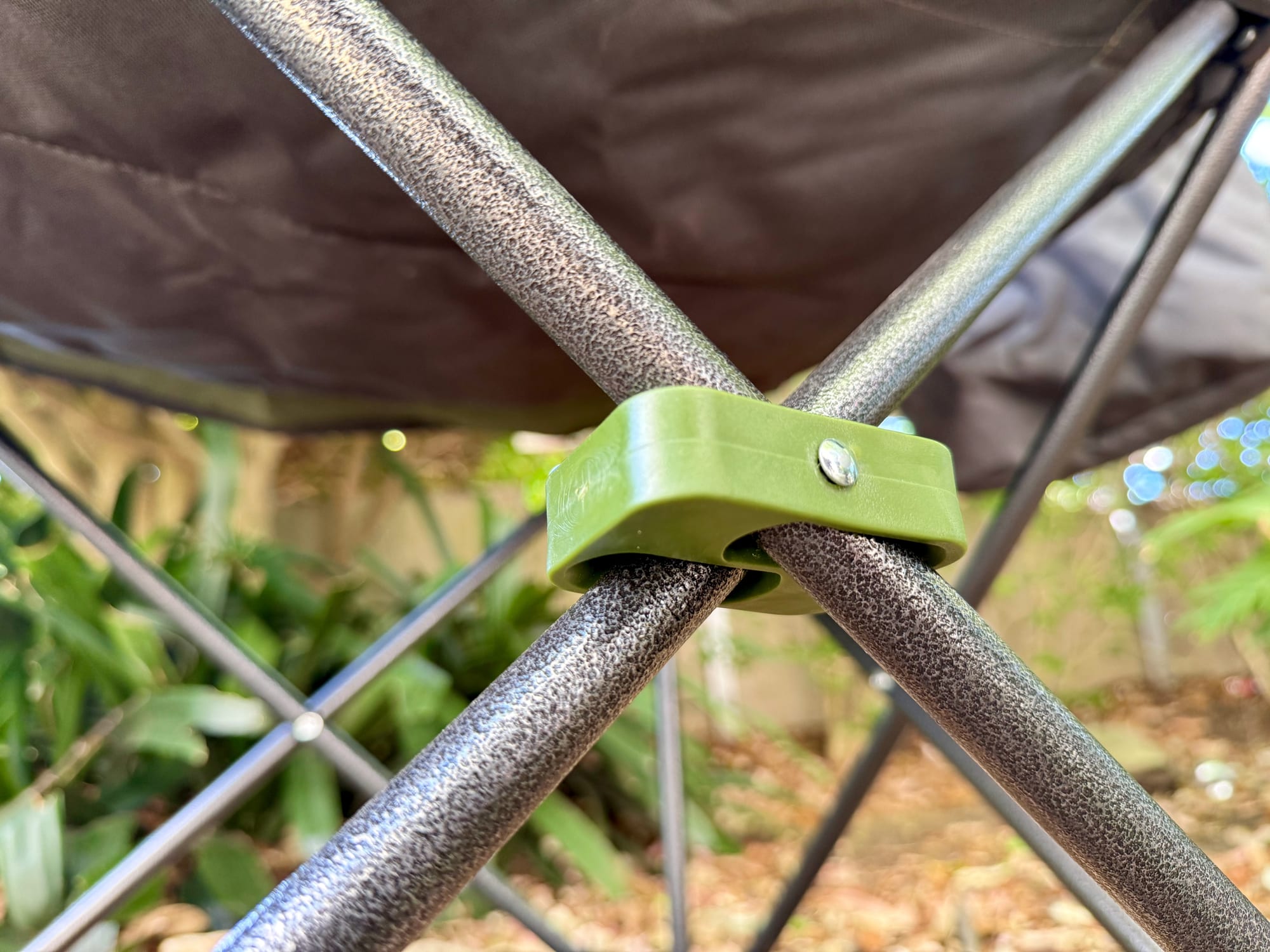 A green hub joining the crossed steel legs of the Wanderer Premium chair