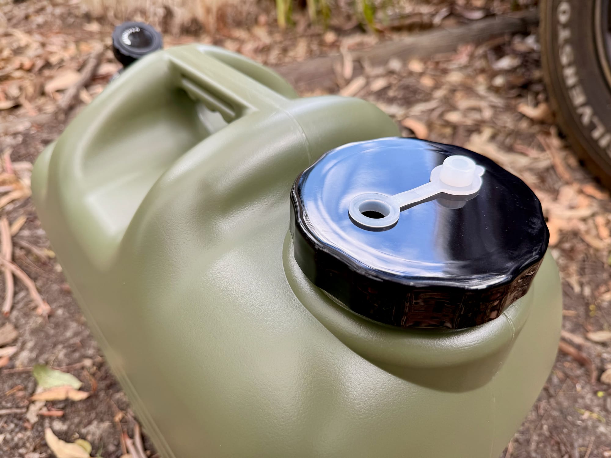 The wide black screw lid with its vent plug on top of the container