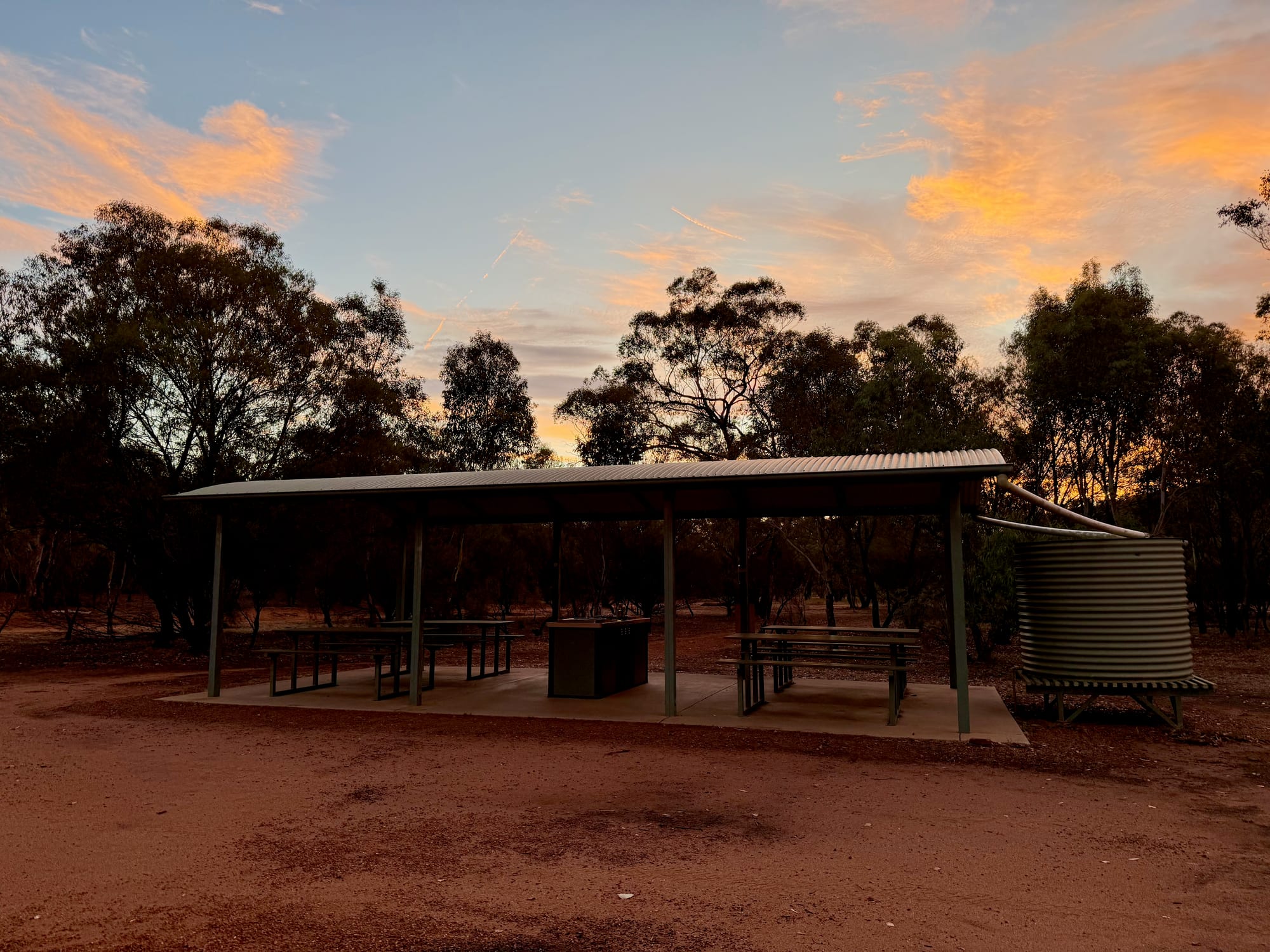 The picnic shelter and rainwater tank at Woolshed Flat Campground at sunset