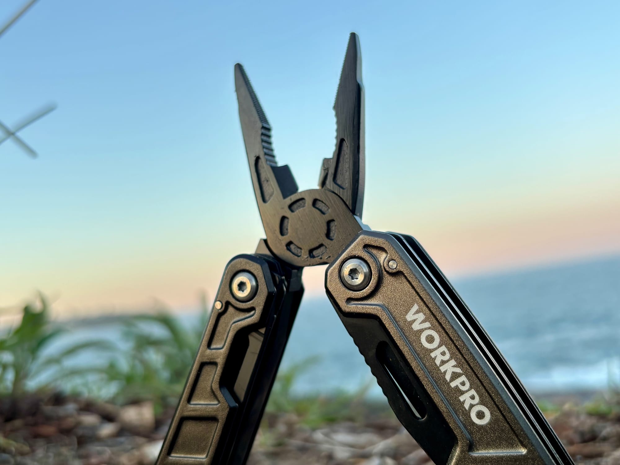 Close-up of the open pliers of the Workpro 11-in-1 multitool, against a sunset sky over the sea