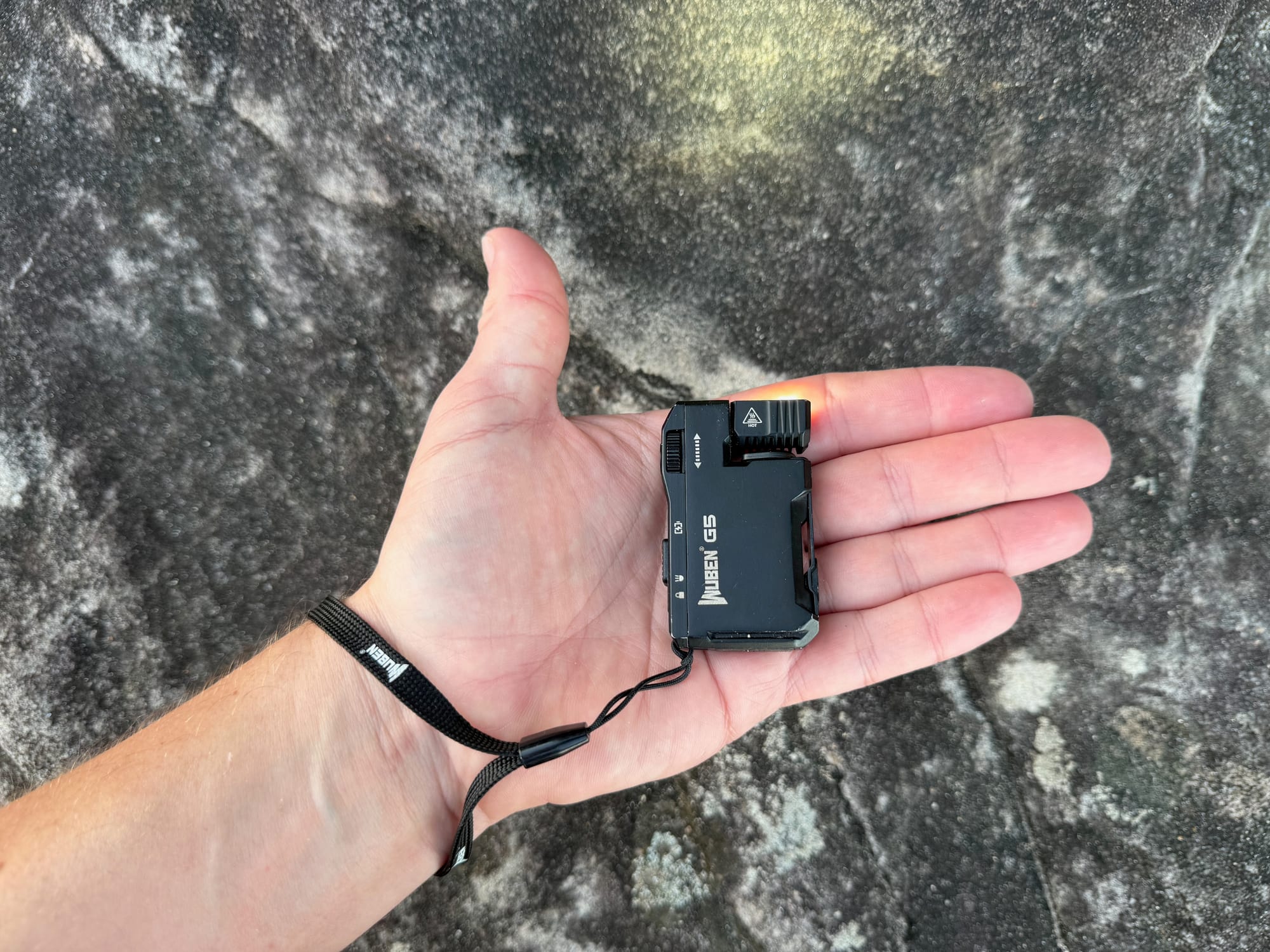 The Wuben G5 lying in the palm of a hand, with its lanyard around the wrist