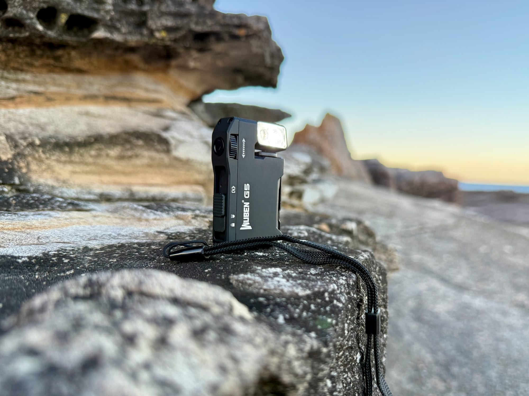 The Wuben G5 standing on the rocks at dusk with its white light on