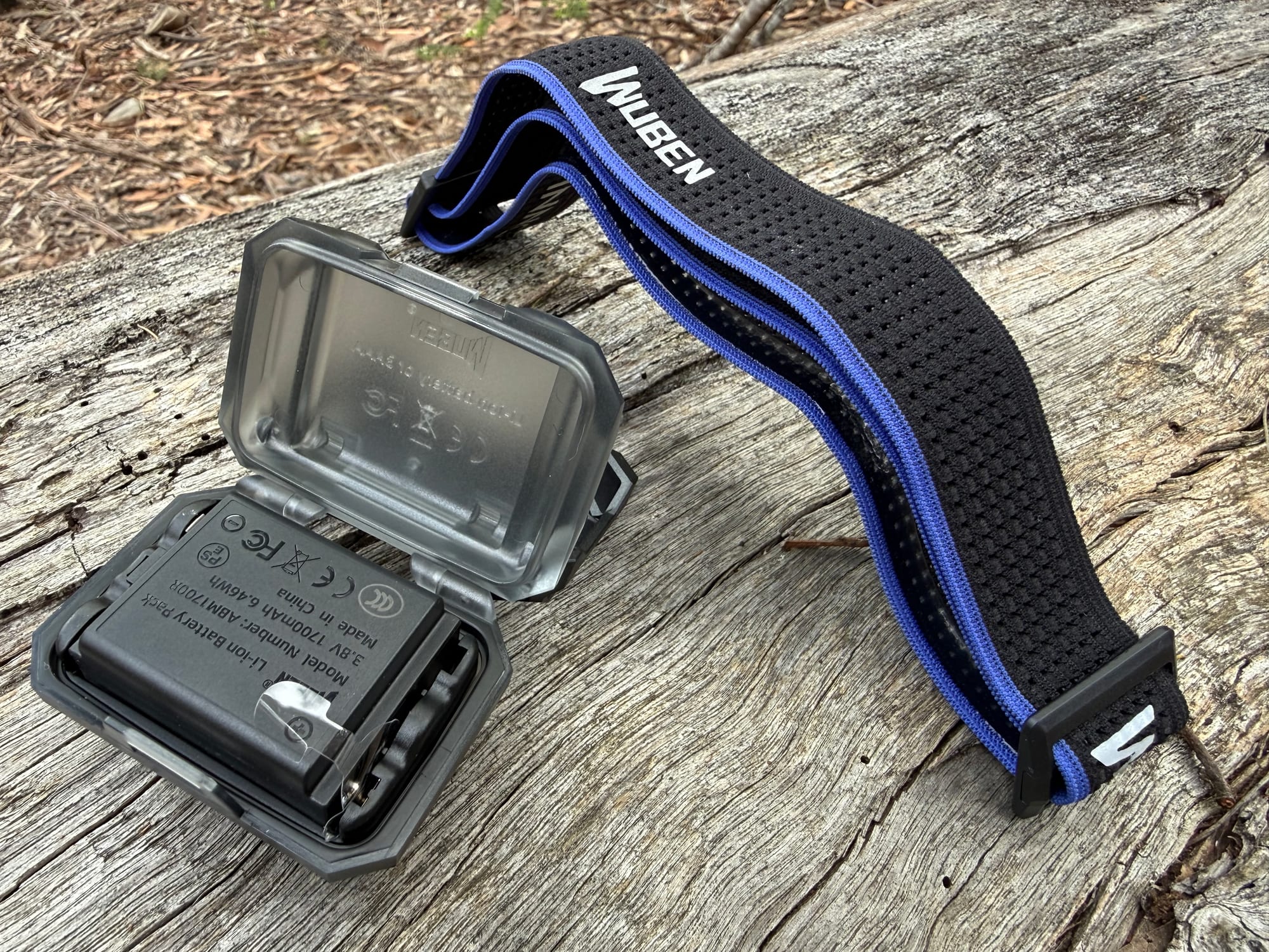 The Wuben H4’s battery pack and its open case next to the black and blue headband