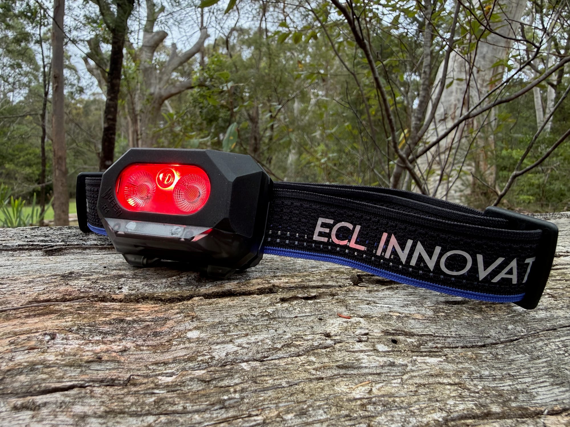 The Wuben H4 with its red light on, on a weathered log
