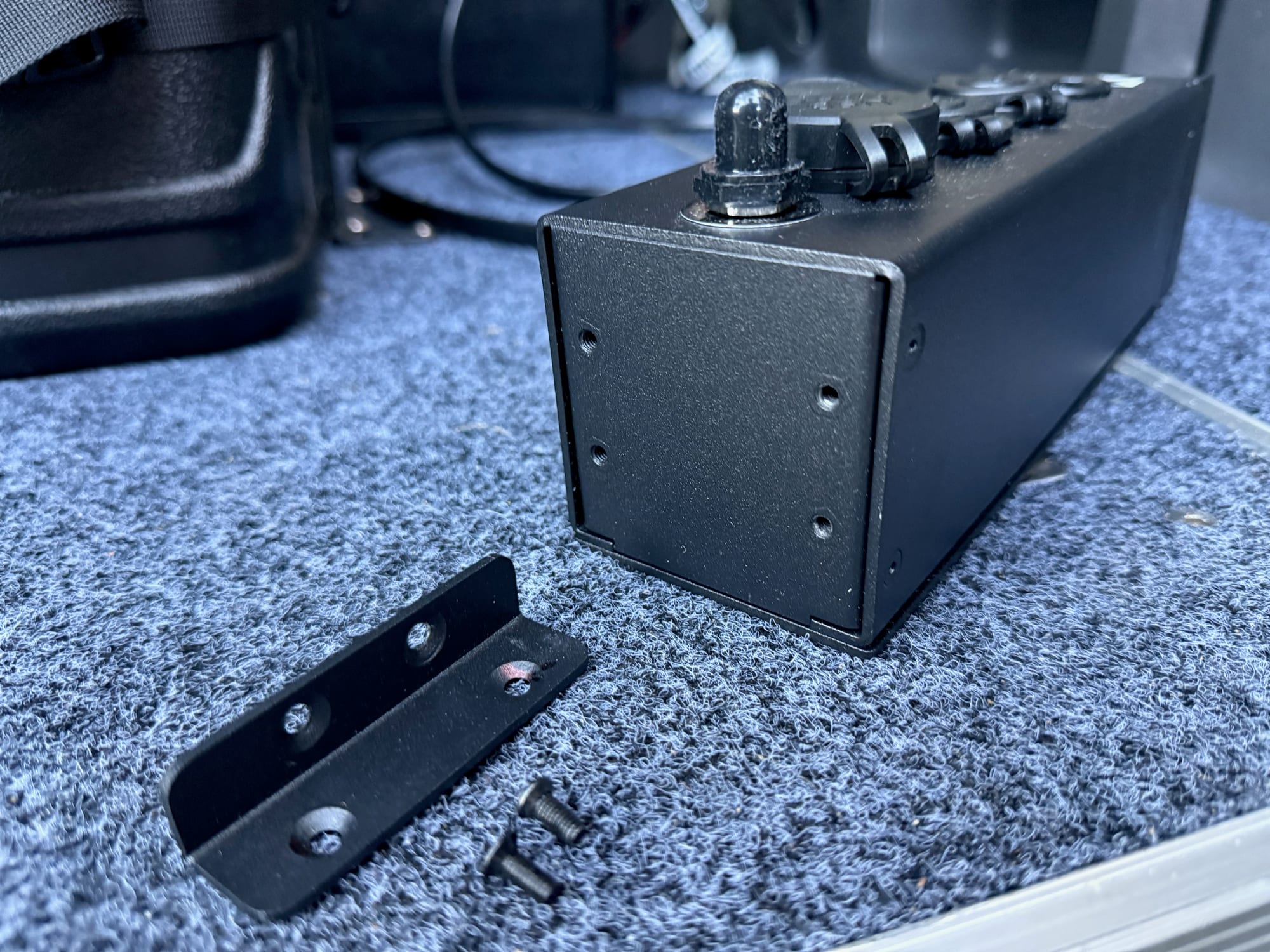 One of the two mounting brackets and its screws, next to the end of the panel it attaches to