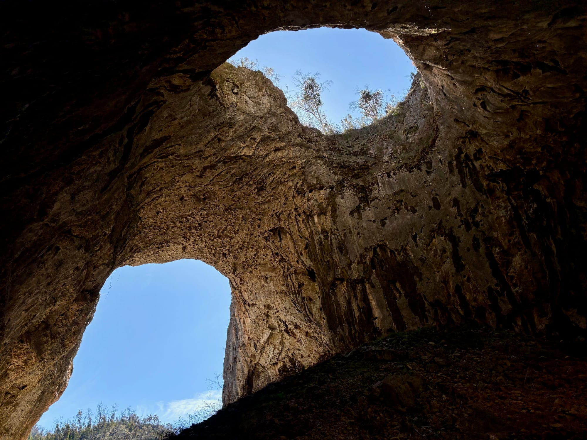 Looking up from inside the Glory Arch at blue sky through a hole in the cave roof