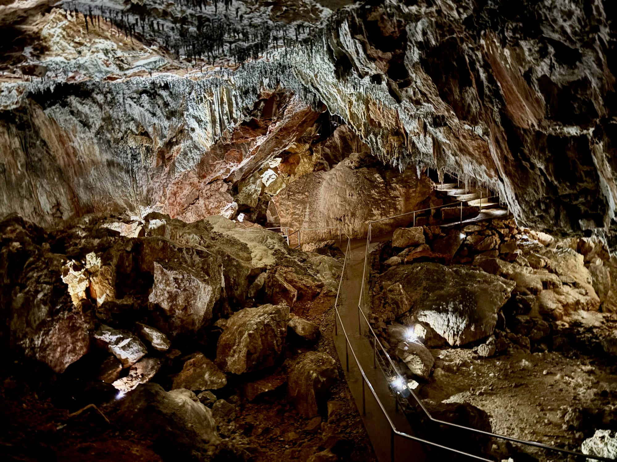 A lit walkway with handrails winding through a large chamber in South Glory Cave