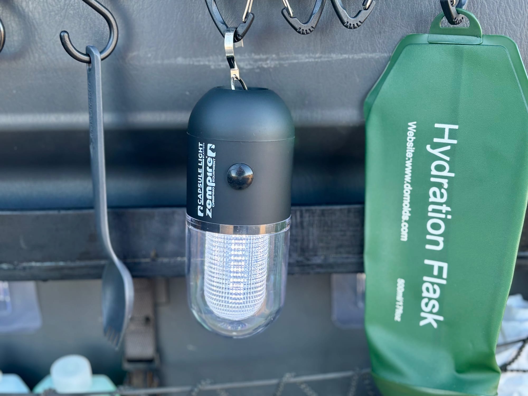 The Zempire Capsule Light switched on, hanging from a carabiner in the back of a 4WD