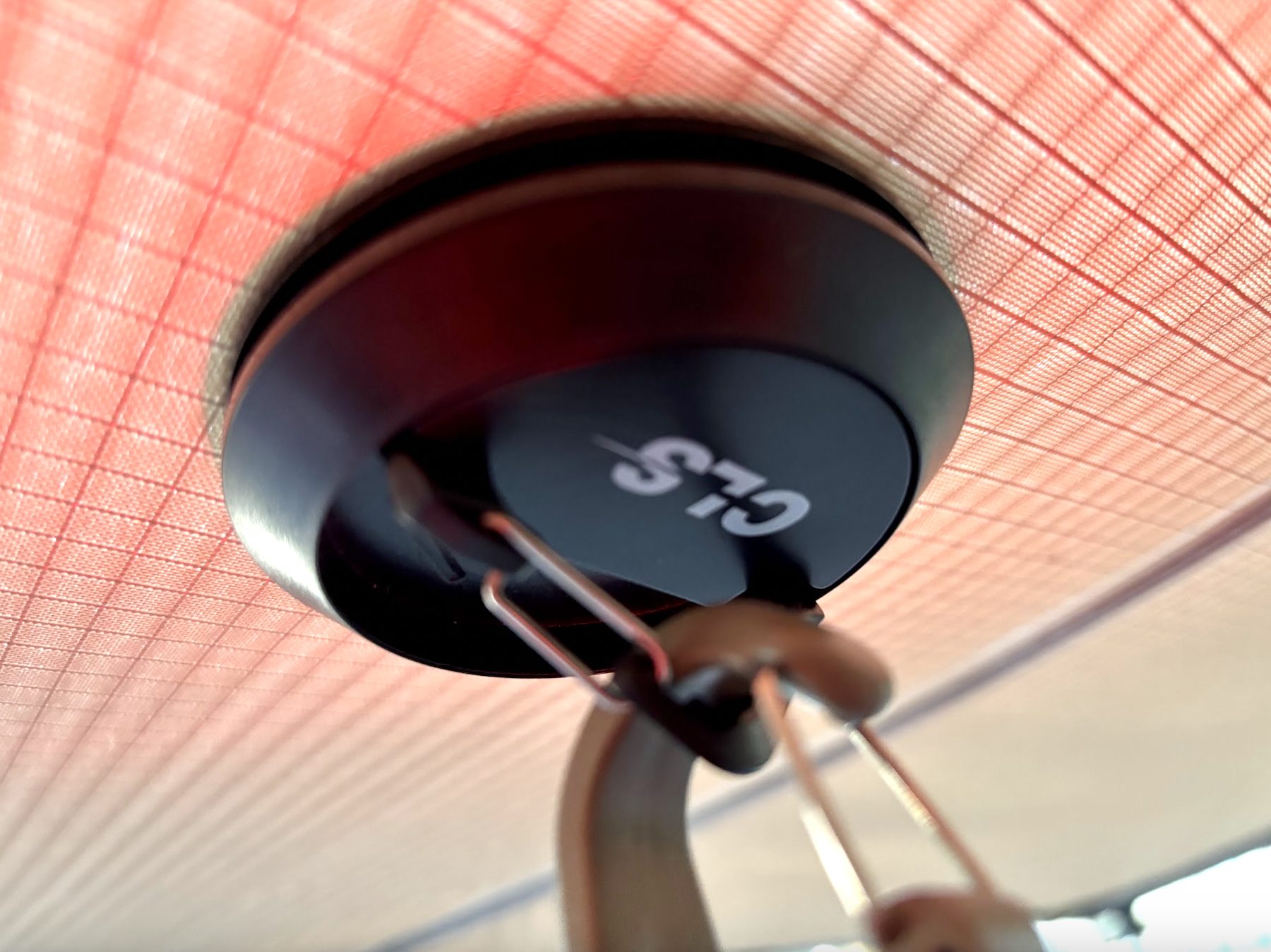 A black magnetic camping hook with a carabiner, stuck to the underside of the awning frame