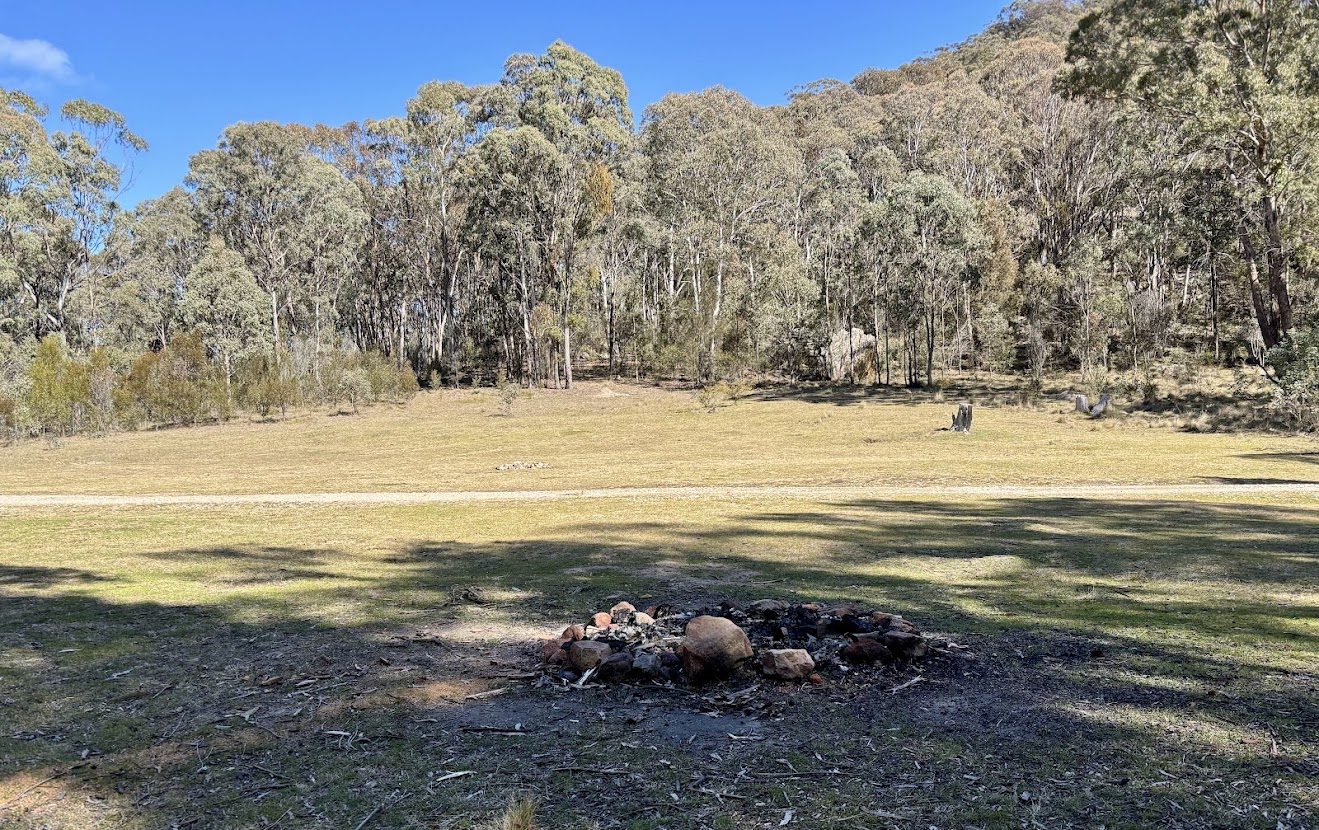 A stone fire pit on the open grass at the Mount Airly camping area