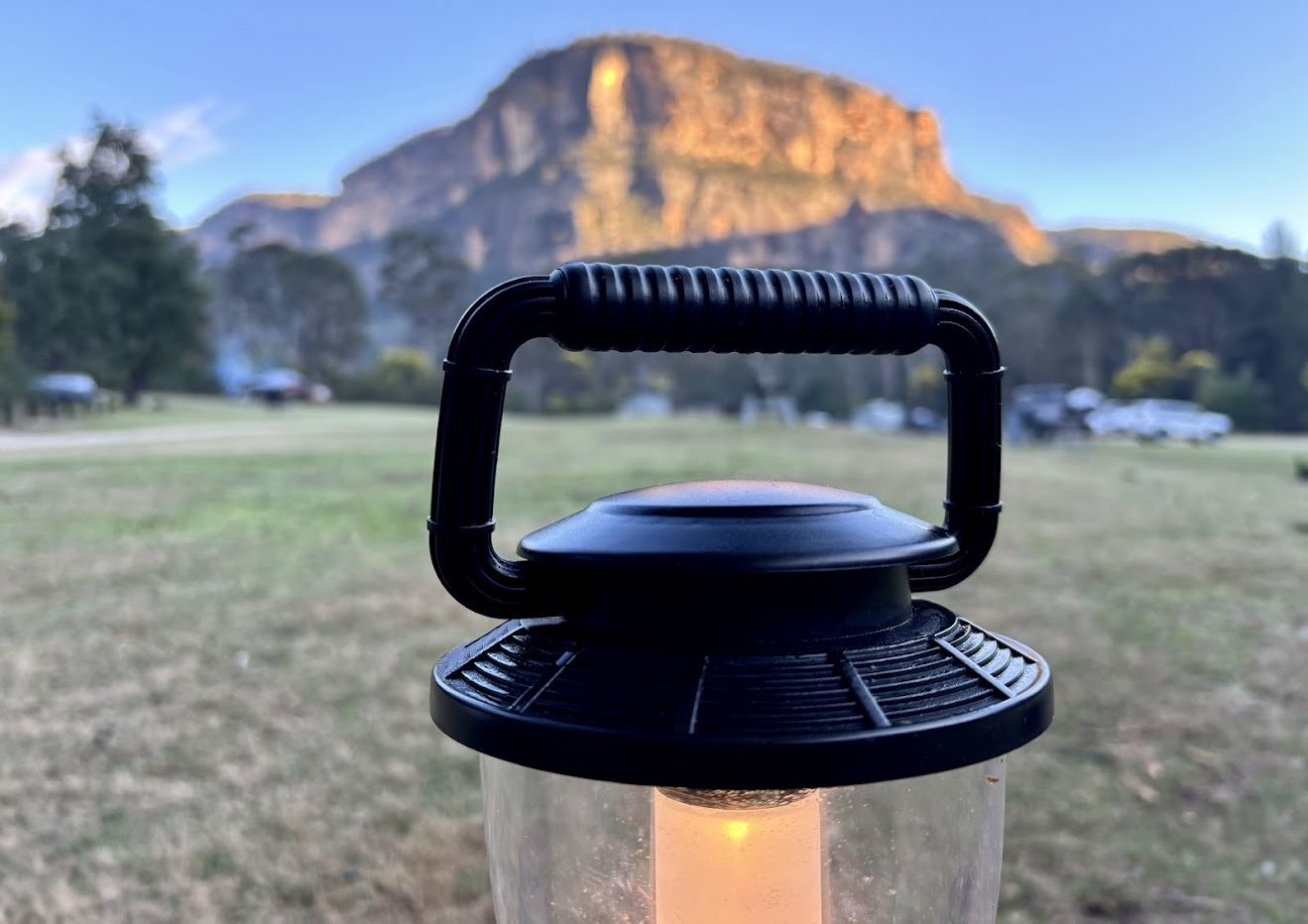 The handle of the Coleman lantern with the campground and cliffs behind