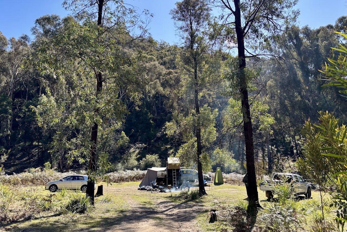 A campervan set up in a secluded clearing among the trees at Mount Airly