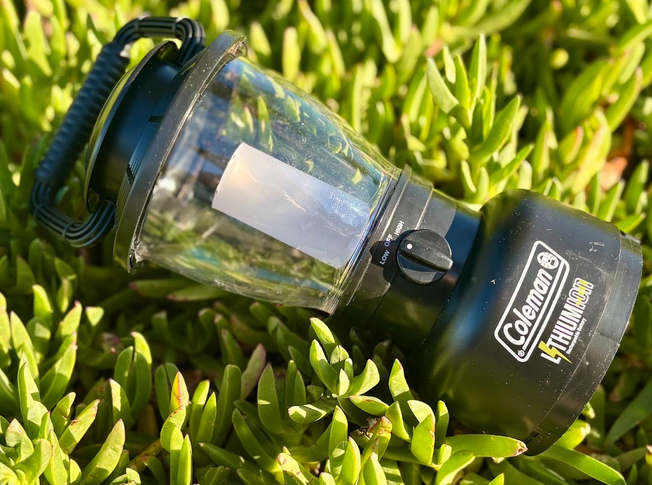The Coleman rechargeable LED lantern lying among coastal plants