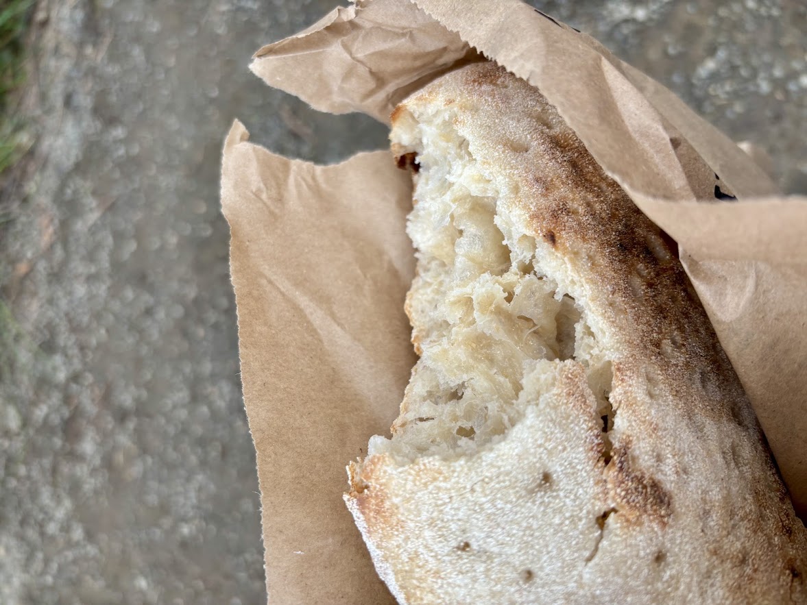 A torn sourdough loaf in its paper bag
