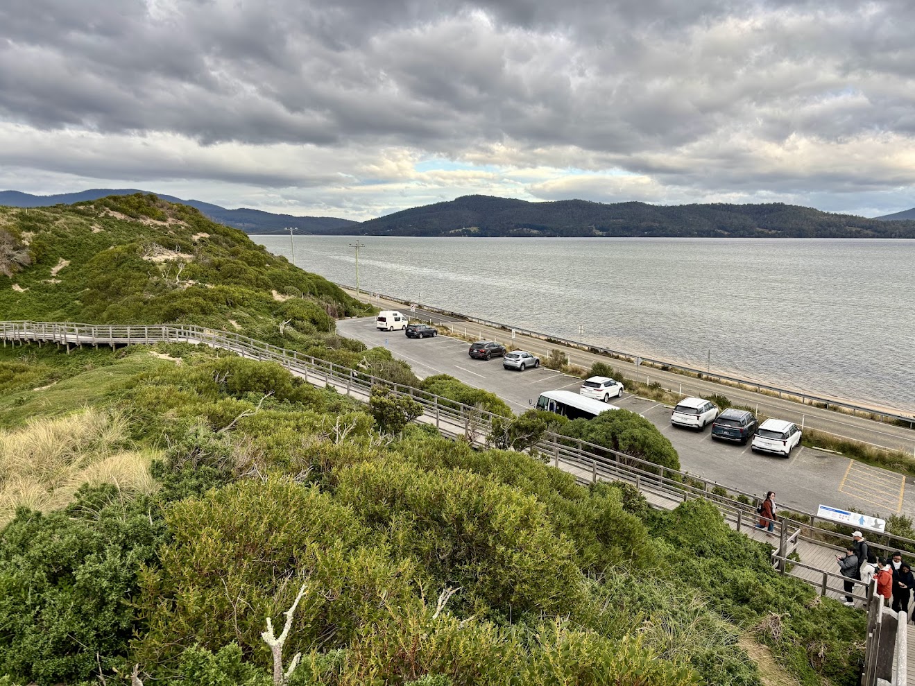 The small car park at the base of the Neck lookout, with cars and the bay behind